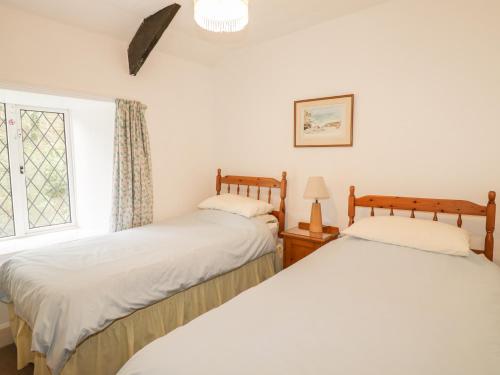 two beds in a room with a window at Miller's House in Tintagel
