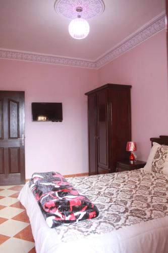 a bedroom with a bed and a tv on the wall at Résidence dikre in Ouarzazate