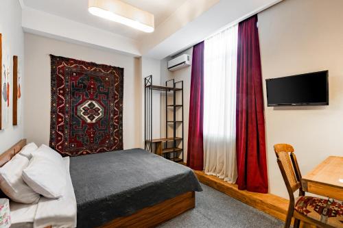 a bedroom with a bed and a tv and a table at Hotel Libretto in Tbilisi City