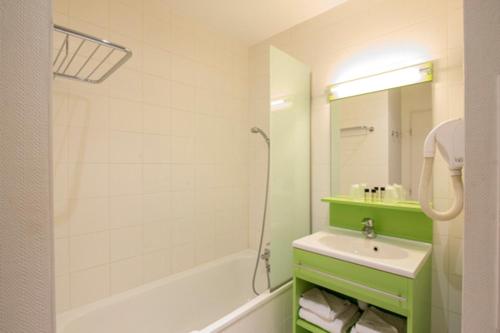 a bathroom with a white tub and a sink at Résidence Villemanzy in Lyon