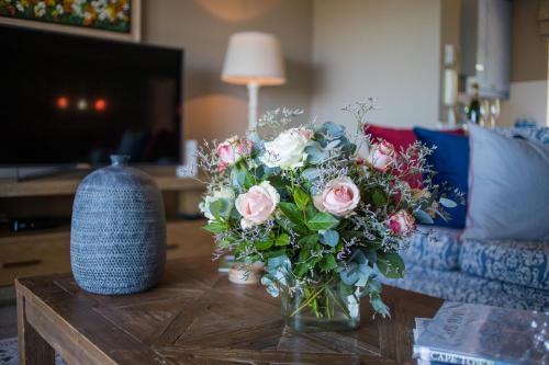 a vase of flowers on a table in a living room at dk villas 1 Harbour View Hout Bay in Hout Bay
