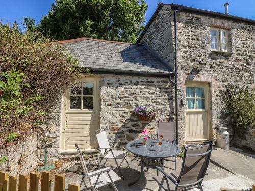 a table and chairs in front of a stone cottage at Honeycrock in Cubert