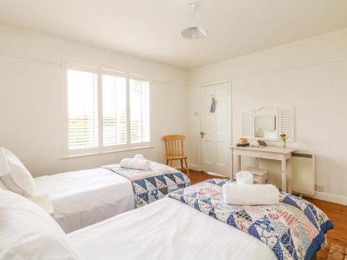 a bedroom with two beds and a desk with a mirror at Bolenowe in Polzeath