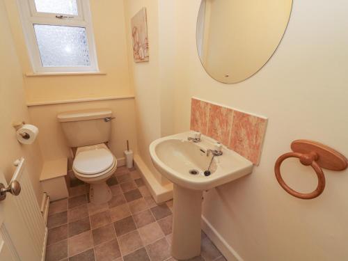 a bathroom with a toilet and a sink and a mirror at Laurel Bank Cottage in Embsay