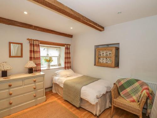 1 dormitorio con 1 cama, vestidor y silla en Pembridge Cottage, en Llanrothal