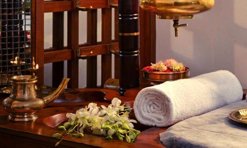 a wooden table with a towel and flowers on it at Gokulam Grand Turtle On The Beach in Kovalam