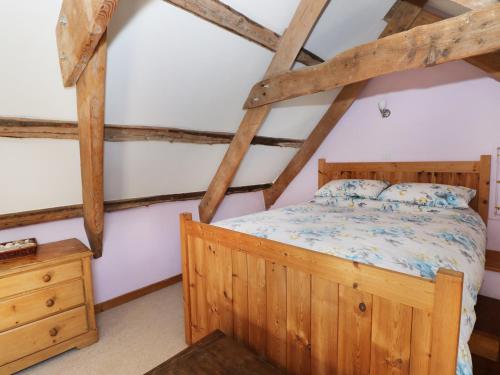 スラングランノグにあるMorfa Isaf Cottageのベッドルーム1室(木製ベッド1台、木製ドレッサー付)