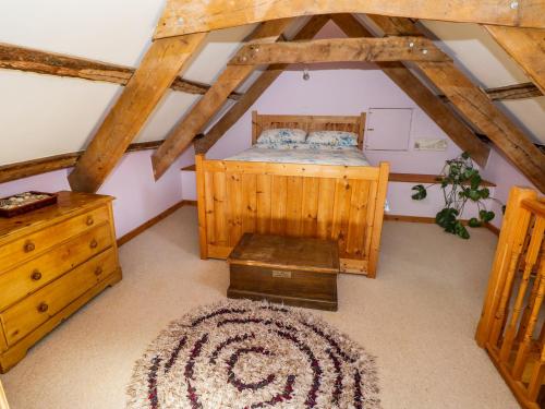 a attic room with a bed and a dresser at Morfa Isaf Cottage in Llangranog