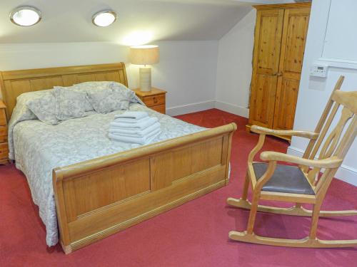 una camera con letto e sedia a dondolo di 1 Primitive Mews a Chelmorton