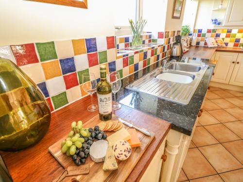 a kitchen with a counter with wine bottles and grapes at Bullace Barn in Thurlstone