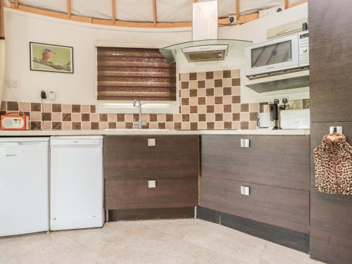 a kitchen with brown cabinets and a white refrigerator at Island Yurt in Beckford