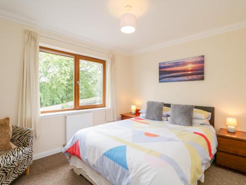 a bedroom with a bed and a window at Woodland Villa in Oban