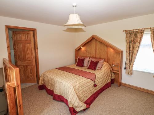a bedroom with a bed with a wooden headboard and a window at Top Stable Cottage in Ireton Wood