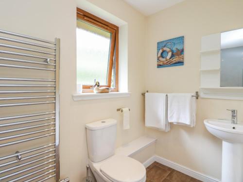 a white bathroom with a toilet and a sink at Woodland Villa in Oban