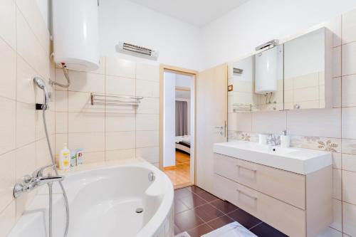 y baño con bañera blanca y lavamanos. en Apartments Flor de Lis en Podstrana