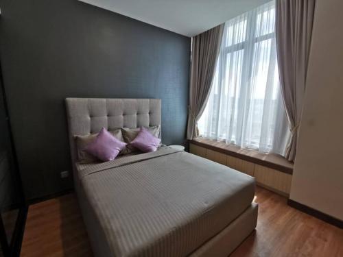 a bedroom with a large bed with purple pillows at Shaftsbury Putrajaya at Alamanda Mall in Putrajaya