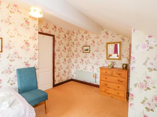a bedroom with a blue chair and floral wallpaper at Barnbrook in Carperby