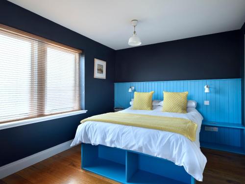 a bedroom with blue walls and a bed with yellow pillows at Signal Box in Newtonmore