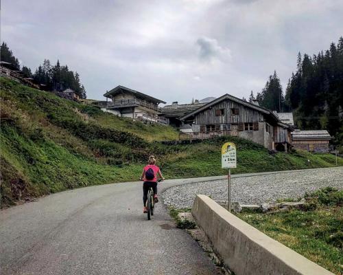 a woman riding a bike down a road at Micro-lodge, Le Petit Nid d'Amour in Montriond