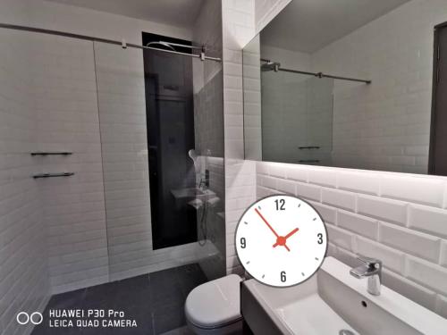 een badkamer met een klok op een wastafel en een toilet bij Shaftsbury Putrajaya at Alamanda Mall in Putrajaya