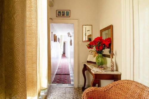 un corridoio con un vaso di fiori rossi su un tavolo di La Casa di Nina a Napoli