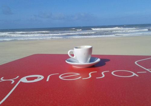 a coffee cup sitting on a red welcome mat on the beach at Greenside of Sea in Corujeira