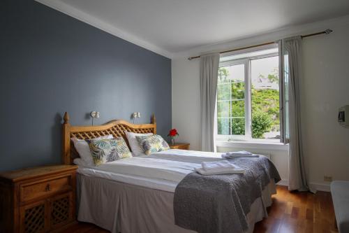 um quarto com uma cama grande e uma janela em Tvedestrand Fjordhotell - Unike Hoteller em Tvedestrand