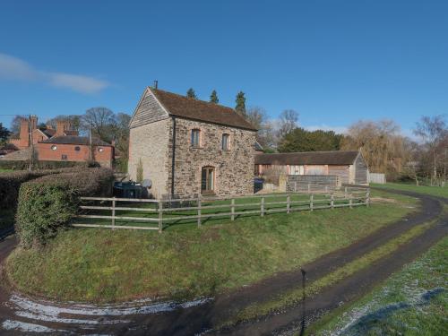 an old stone house on a field with a fence at Glebe Barn in Caynham