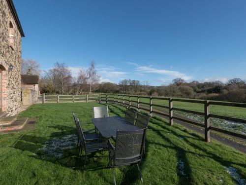 a table and chairs in a field next to a fence at Glebe Barn in Caynham