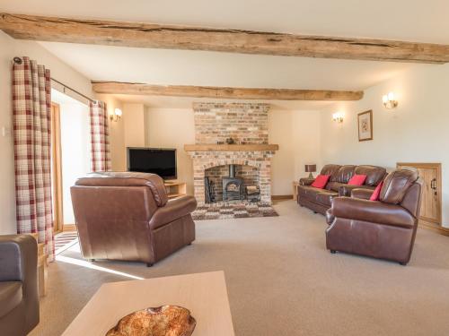 a living room with couches and a fireplace at Glebe Barn in Caynham