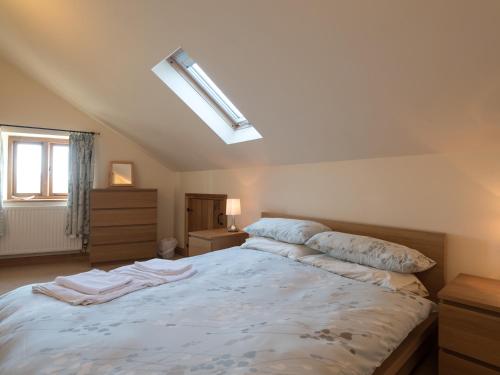 a bedroom with a large white bed with a skylight at Glebe Barn in Caynham