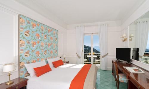 Dormitorio con cama, escritorio y TV en Hotel & Spa Bellavista Francischiello en Massa Lubrense