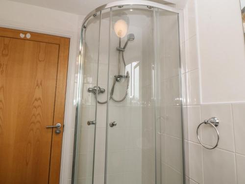 a bathroom with a shower with a glass door at 5 Cae Derwydd in Cemaes Bay