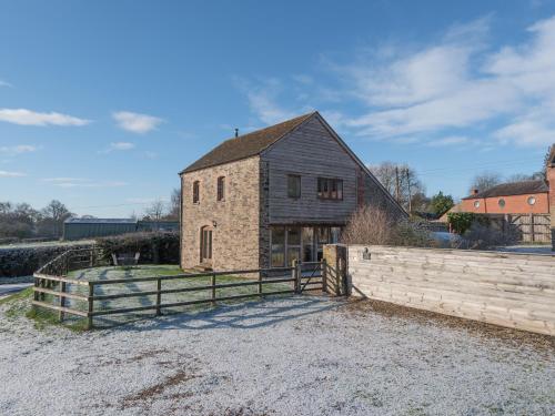 a stone barn with a fence in front of it at Glebe Barn in Caynham