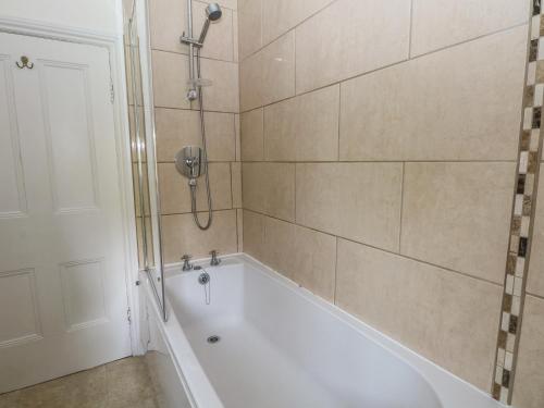 a bathroom with a white tub and a shower at Gun End Cottage in Rushton Spencer