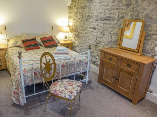 a bedroom with a bed and a chair and a mirror at 2 Primitive Mews in Chelmorton