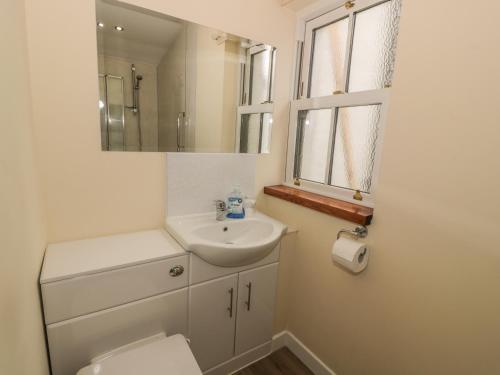 a bathroom with a sink and a toilet and a mirror at Alma Cottage in Tyndrum