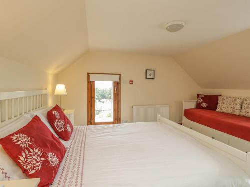 um quarto com uma grande cama branca com almofadas vermelhas em 10 Monarch Country Apartments em Newtonmore