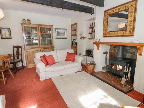 een woonkamer met een witte bank en een open haard bij Lane Fold Cottage in Grassington