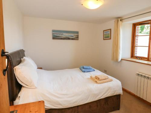 a bedroom with a bed with white sheets and a window at Hartland View in Great Torrington