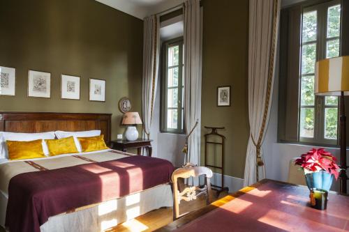 um quarto com uma cama, uma mesa e janelas em Villa Biondelli Wine & Suites em Cazzago San Martino