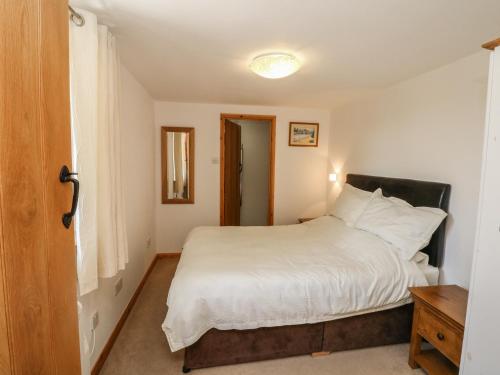 a bedroom with a white bed and a window at Lundy View Cottage in Great Torrington