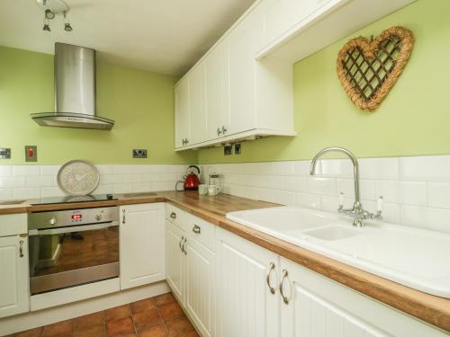 a kitchen with white cabinets and a heart ornament on the wall at Gill Head Farm in Mungrisdale