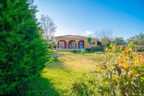 a small yellow house with a yard with plants at Loukas Farm House in Ayios Kirikos