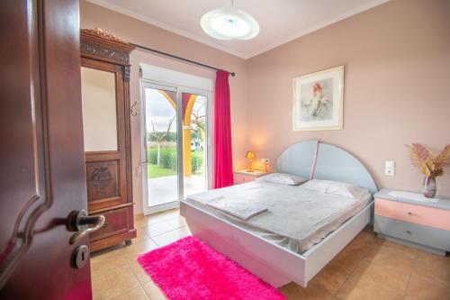 a bedroom with a bed and a door with a pink rug at Loukas Farm House in Ayios Kirikos