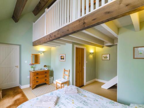 a bedroom with a bed and a wooden staircase at The Byre at High Watch in Lanehead