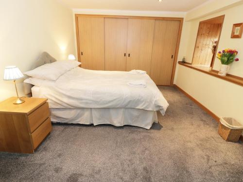 a bedroom with a large white bed and a wooden cabinet at The Old Brewery Store in Gatehouse of Fleet