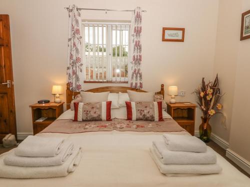 - une chambre avec un grand lit et des serviettes dans l'établissement Little Argham Cottage, à North Burton