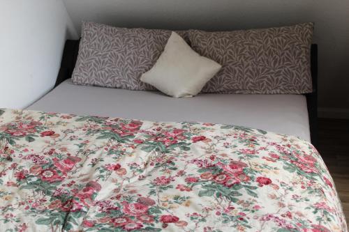 - un lit avec une couette à fleurs et 2 oreillers dans l'établissement Gepetto Ferienhaus Wissenbach, à Hademstorf