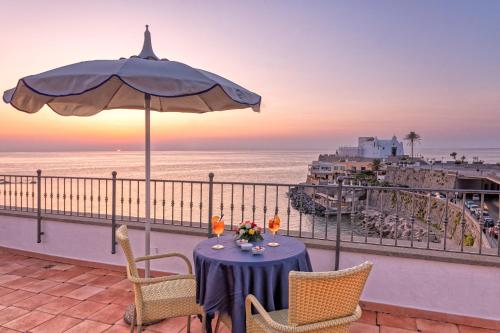 伊斯基亞的住宿－尼圖諾酒店，阳台上的桌子上摆放着遮阳伞和海洋